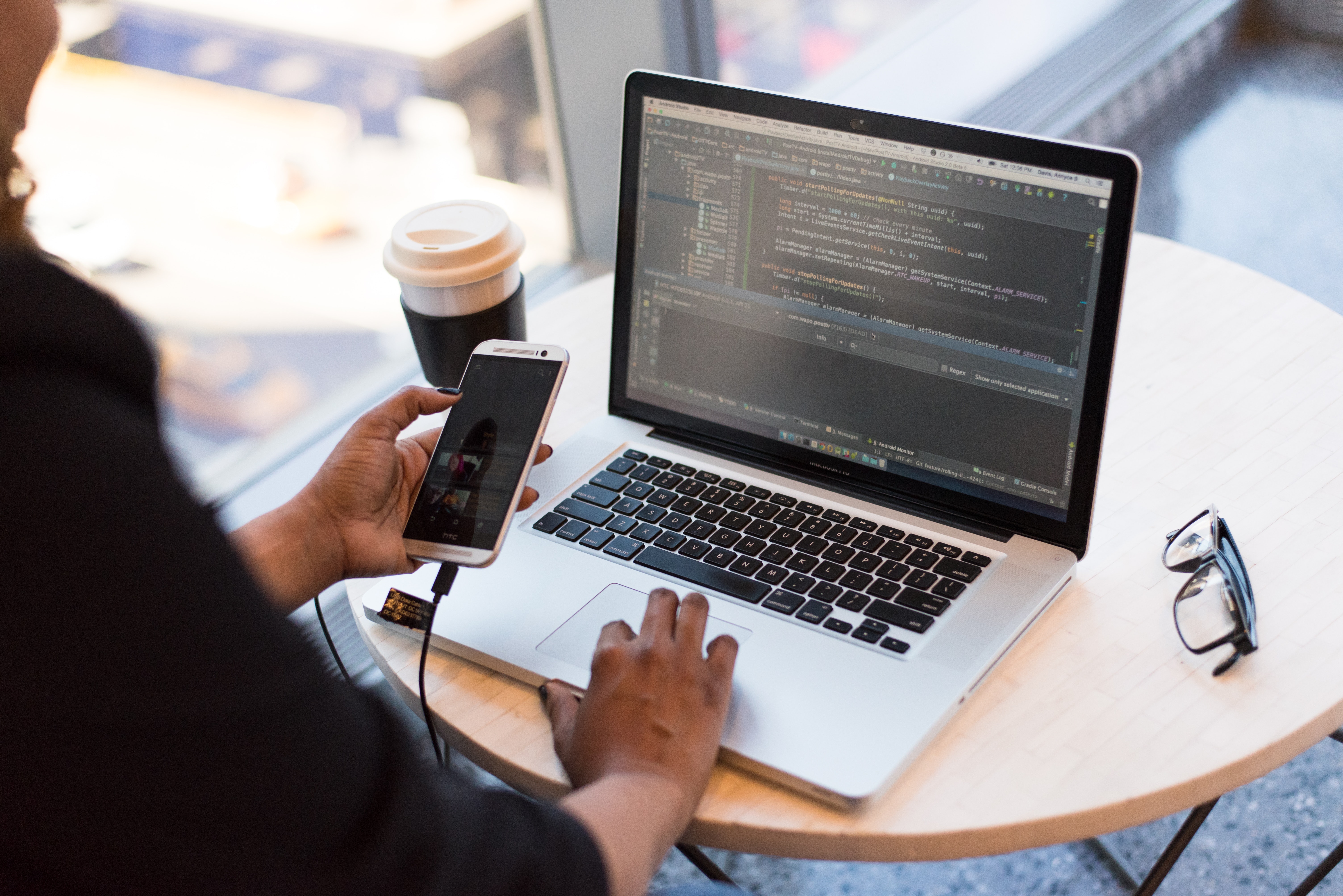 person-looking-at-phone-and-at-macbook-pro-1181244